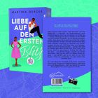 "Liebe auf den ersten Blitz", von Martina Gercke. Blaues Cover mit Illustration: Mann auf großem Text, Frau in pinkem Kleid.