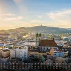 Innsbruck 6. Stadtplatz mit bunten Gebäuden, Uhrturm, Alpen im Hintergrund, blauer Himmel. Kalenderdaten unten.