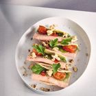 Drei Garnelen-Tacos mit Tomaten, grünen Blättern und knusprigen Garnierungen auf einem weißen Teller.