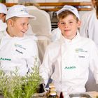 „EUROPA MINIKÖCHE“ steht auf den Mützen zweier Kinder in weißen Kochjacken namens Benedikt und Lorenz.
