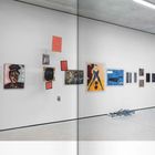 Auf weißer Wand sind diverse Gemälde und Zeichnungen arrangiert. Unten steht: "Werke aus den Studienjahren, 1954-65".