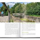 "Wo geht es hier zur Ladestation?" Überschrift. Ein Radfahrer fährt auf einem Weg neben einer Kanalschleuse, umgeben von Bäumen.