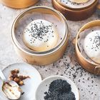 Körbe mit gedämpften Brötchen, bestreut mit schwarzen Sesamsamen. Teller mit Sesam und einer klebrigen Paste.