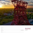 Text: "46. Woche November 2027." Darstellung: Ein rotes Fördergerüst bei Sonnenuntergang über einer Stadtlandschaft.