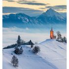 "49 DEZEMBER MO 06 DI 07 MI 08 DO 09 FR 10 SA 11 SO 12. Verschneiter Hügel mit Kirche, dahinter schneebedeckte Berge."