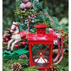 Kalenderwoche 51, Dezember 20-26. Rote Laterne mit Kerze, Tannenzweige, Zapfen, Beeren, Spielzeugpferd auf Schaukelbrett.