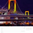 49. Woche, Dezember 06 Mo, 12 So, 3. Advent. Abbildung: Rainbow Bridge in Tokio, abends beleuchtet in Gelb und Orange.