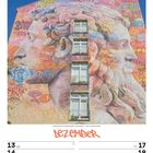 Eine große Wandmalerei zeigt zwei monumentale, farbenfrohe Porträts, die ineinander verschmelzen. Darunter ein Kalender für Dezember 2027.