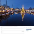 51. Woche, Dezember 2027. Am Hafen leuchten festlich geschmückte Boote, ein großer Weihnachtsbaum spiegelt sich im Wasser.