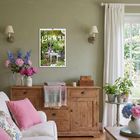 Kalender mit "Garten 2024". Wohnraum, Holzmöbel, Sofa mit Kissen, Pflanzen, Fenster mit Blick ins Grüne.