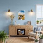 Ein Raum mit einem Kalender an der Wand mit der Aufschrift „küste 2024“. Holzkommode, Leuchtturm-Deko, Pflanzen.