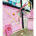 "BARBIE PEEPSHOW STARTS HERE" steht groß an einer pinken Wand. Eine stilvolle Retro-Ästhetik mit Schildern und Pfeilen.