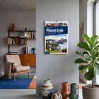 Ein Wochenplaner mit "Abenteuer Planet Erde", zeigt Landschaften. Im Raum sind ein Sessel, Bücherregal und Pflanzen.