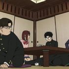 Eine Gruppe von fünf Jugendlichen in Schuluniform in einem traditionellen japanischen Raum, sitzen und knien um einen Tisch.