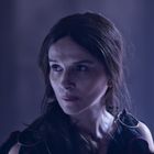 Eine Frau mit langen dunklen Haaren schaut seitlich. Die Beleuchtung ist gedämpft mit violettem Ton.