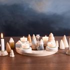 Ein Holzkreisel mit Kerzen und miniaturhaften Bäumen auf einem Holztisch vor einem dunklen Hintergrund.