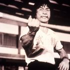 Ein Mann mit entschlossenem Gesichtsausdruck hält eine lange Stange. Sein Hemd zeigt chinesische Schriftzeichen.