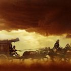 Ein Planwagen wird von Pferden gezogen, darüber dunkle Wolken. Eine Person lenkt, eine weitere steht mit Speer daneben.