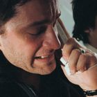 Zwei Männer im Inneren eines Flugzeugs, einer spricht in ein Telefon mit besorgtem Gesichtsausdruck.