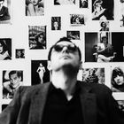 Viele schwarz-weiße Porträtfotos klassischer Filmstars an der Wand, mit unscharfem Mann im Vordergrund.