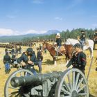 Eine Gruppe von Soldaten in historischen Uniformen, Pferde und Kanonen, in einer weiten Wiesenlandschaft mit Bergen im Hintergrund.