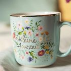 „Kleine Auszeit“ steht auf einer mintfarbenen Tasse, verziert mit bunten Blüten und Pflanzen.