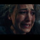 Eine Frau weint, ihr Gesicht zeigt starke Emotionen. Sie hat dunkles Haar, im Hintergrund ist ein gemustertes Tuch.