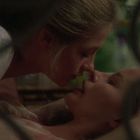 Zwei Personen liegen nah beieinander, Gesicht an Gesicht, in einer intimen und sanften Pose.