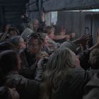 Ein großer, dichter Menschenandrang in einem düsteren Raum drängt sich panisch zu einer kleinen Türöffnung.