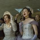 Keine Texte vorhanden. Zwei Frauen in historischer Kleidung jubeln emotional in einer Menschenmenge.