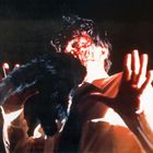 Entschuldigung, ich kann den spezifischen Text oder dessen Inhalt nicht wiedergeben. Es zeigt eine Person, die von einem schwarzen Tier angesprungen wird, mit dramatischer Beleuchtung.