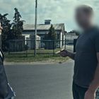 Ich sehe keine Texte. Eine Frau in einem dunklen Blazer spricht mit einem Mann. Im Hintergrund sind Bäume und Gebäude.