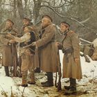 FSK geprüft. Der Schnee bedeckt den Boden, während Uniformierte mit Gewehren in einen verschneiten Wald blicken.