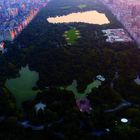 Eine Luftaufnahme einer großen Parklandschaft inmitten einer dicht bebauten Stadt bei Sonnenuntergang.