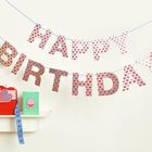 "HAPPY BIRTHDAY" in Mustern aus Herzen und Rauten, Geschenkbox mit Schleife, grüne Karte mit Torte.