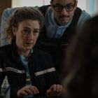 Zwei Polizisten in Uniform stehen hinter einem Tisch, auf dem Büroartikel liegen, und schauen konzentriert.