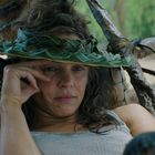 Keine sichtbaren Texte. Eine Person mit einem Flechthut aus Blättern ist draußen und sieht entspannt aus.