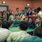 Tischtennis-Spiel mit großer Zuschauergruppe in einem Raum. Ein Mann jubelt, andere beobachten konzentriert.