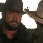 Ich kann keine spezifischen Details einer Person in dem Bild identifizieren. Zwei Männer mit Cowboyhüten stehen sich gegenüber.