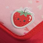 Ein lachender Erdbeeraufnäher mit Gesicht auf rosa Stoff, umgeben von kleinen Herzformen.