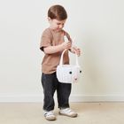 Ein Kind hält einen weißen Korb mit Kaninchengesicht und Ohren, trägt ein braunes T-Shirt und dunkle Jeans.