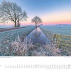 November. Ländliche Winterlandschaft vor Sonnenaufgang in Noorden, Niederlande. Frostige Felder, Bäume, Wassergraben.