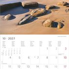 Kalender für Oktober 2027. Wochentage in mehreren Sprachen. Bild eines sonnigen Strandes mit Felsen am Meer.