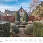 Kalenderseite mit Landschaft: Beschnittener Garten vor einem traditionellen Fachwerkhaus, klarer Himmel.