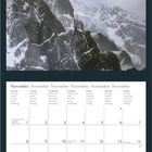 Kalenderseite für November mit Wochentagen in mehreren Sprachen. Oben fliegen Flamingos über schneebedeckte Berge.