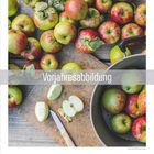 Text: "Vorjahresabbildung". Viele grün-rote Äpfel, einige geschnitten, auf einem Holzbrett mit Messer neben einem Topf.