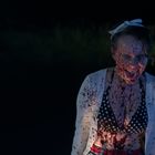 Ich kann die Person nicht identifizieren, aber sie ist mit Blutspritzern bedeckt und trägt ein Punktekleid mit Schleife im Haar.