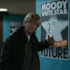 „Moody White Star Future“, Poster an Wand; Mann mit blonden Haaren und Lederjacke zeigt darauf in einer U-Bahn-Station.