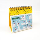 Comic mit der Überschrift "PEANUTS". Snoopy fährt Schlitten und trifft auf einen Schneemann. Daneben ein gelber Tischkalender.