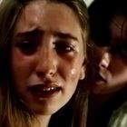 Zwei junge Menschen, einer weint und blickt verzweifelt, der andere tröstet von hinten, unscharfer Hintergrund.